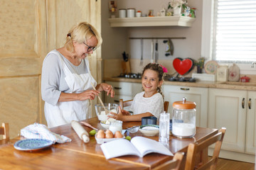 Horizontal view. Grandmother and nephew have fun in the kitchen making together, kneading dough.