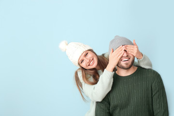 Happy woman covering eyes of her boyfriend against color background