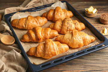 Tasty croissants on baking tray