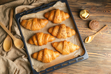 Tasty croissants on baking tray