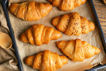 Tasty croissants on baking tray