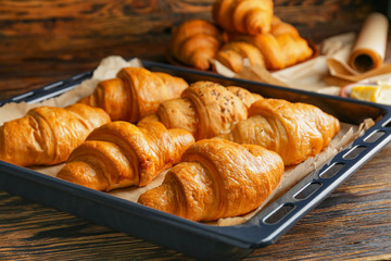 Tasty croissants on baking tray