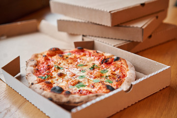 Pizza delivery concept. Baked products in a cardboard box against a wooden background. Baked tasty margherita pizza in Traditional wood oven in Neapolitan restaurant, Italy. - 315849984