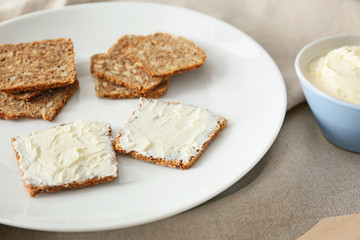 Fototapeta na wymiar Plate with fresh bread and tasty cream cheese on table