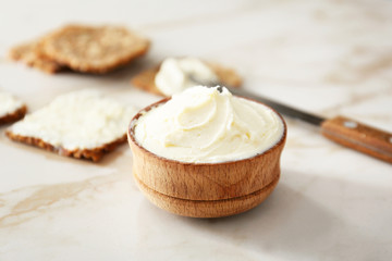 Bowl with tasty cream cheese on table