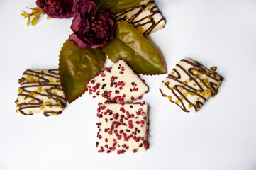 Beautiful cookies in chocolate close-up with flowers on a white background