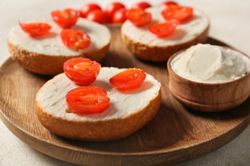 Fresh buns with tasty cream cheese and tomato on plate, closeup