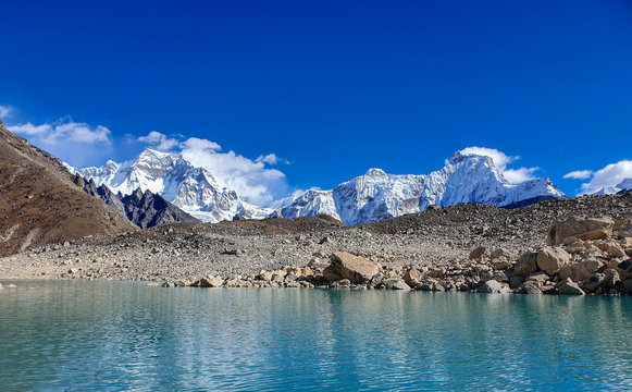 Ngozumpa Tsho, the fifth Gokyo lake., hills and snow-capped mountains. Sunny day and marvellous blue sky. Gokyo lakes and Cho Oyu base camp trek, Solokhumbu, Nepal.