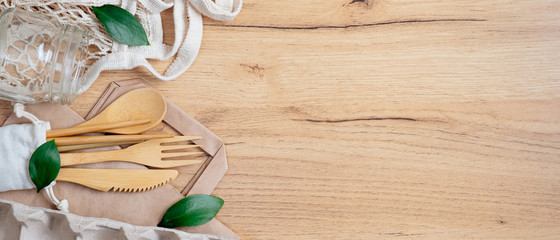 Sustainable lifestyle. Zero waste, plastic free concept. Top view cotton shopping bag, glass jar, bamboo tableware and green leaves on wooden table