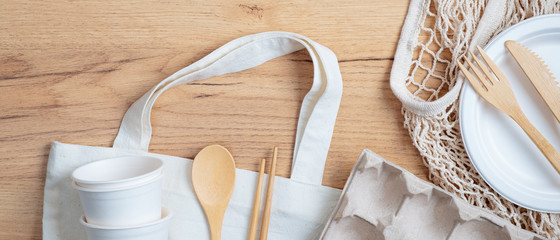 Top view eco-friendly utensils, bamboo cutlery, cotton and string shopping bags, carton eggs box on wooden table. Sustainable lifestyle. Zero waste, plastic free concept