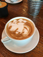Latte art with cream in white cup.