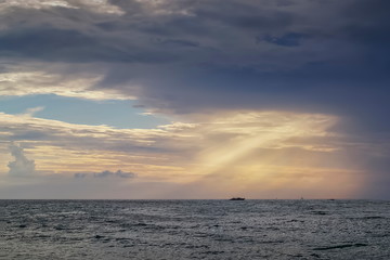 view evening of dark clouds moving with sun rays shining to a small boat in the sea, sunset at Ra Wi island, Tarutao National Marine Park, Stun, south of Thailand.
