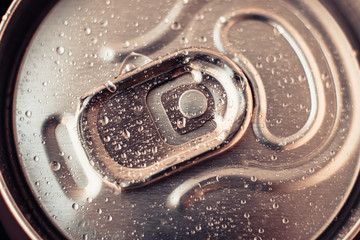 Metallic drink can with water drops. Shiny beer can close-up. Golden bottle of drink, lid of packaging of cola. Top view.