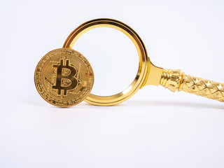 Golden Bitcoin replica and magnifying glass on white   background.Business and finance concept.