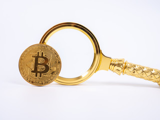 Golden Bitcoin replica and magnifying glass on white   background.Business and finance concept.