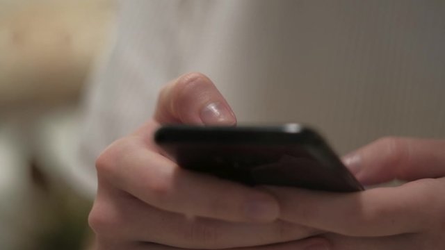 Close up of young woman hands using mobile phone, scrolling for content at home evening