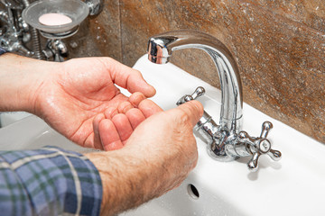 The man washes his hands in the sink. The concept of care for cleanliness, personal hygiene....