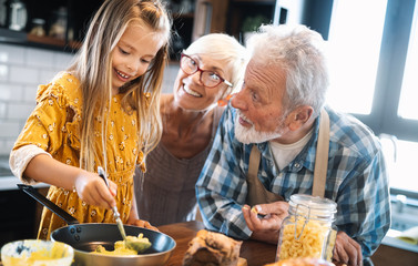 Happy grandparents with grandchildren making breakfast in kitchen