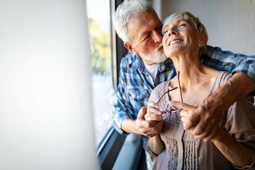 Happy smiling senior couple embracing together at home