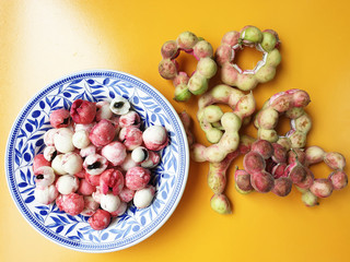 Peeled Manila Tamarind or makham thet in Thailand onto a beautiful patterned dish with many green...