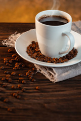 White coffee cup and coffee beans on wooden background