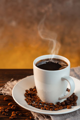 White coffee cup and coffee beans on wooden background