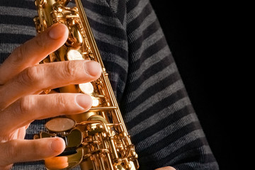 soprano saxophone in the hands of a guy on a black background