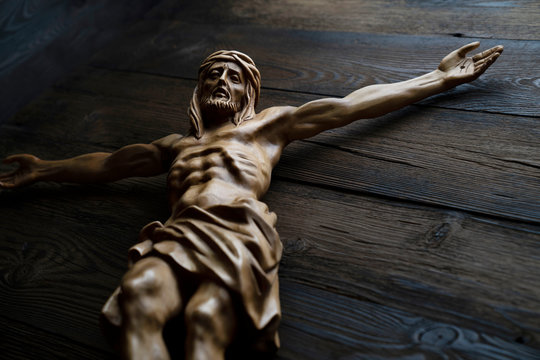  Cruciefied Jesus figure isolated on rustic dark brown table.
