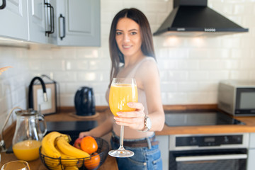 Beautiful girl holds out a glass with orange juice