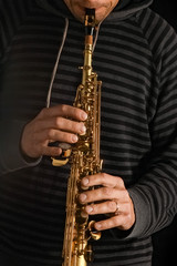 Obraz premium soprano saxophone in the hands of a guy on a black background