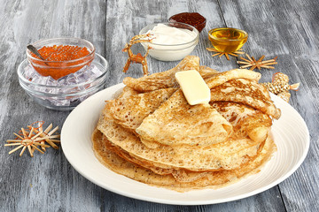 Plate with delicious thin pancakes and topping on wooden background