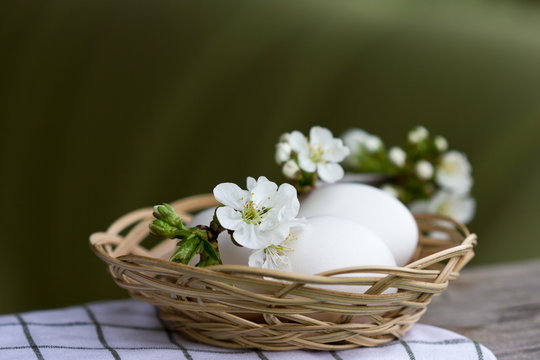 Spring cherry blossoms, white eggs in a wicker basket. The concept of holiday and spring.