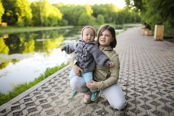 Girl leads hands little sister in park, outside