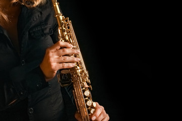 Obraz na płótnie Canvas soprano saxophone in the hands of a girl on a black background