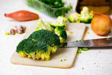 Broccoli, onion, garlic and knife on kitchen board.
