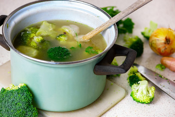 Pot with broccoli soup on table.