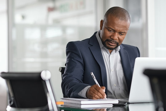 Mature businessman writing on documents