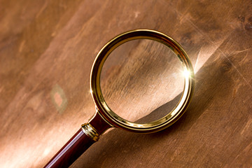 magnifying glass with sun glare on a wooden background