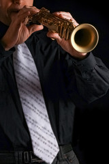 Obraz premium soprano saxophone in the hands of a guy on a black background
