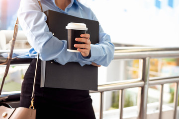 Businesswoman standing on street and holding hot coffee.
