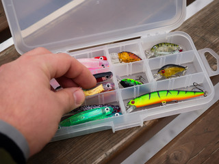 Fishing lures and accessories in the box background. Focus in the center of the bait.