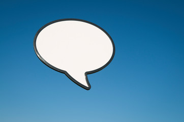 Single graphic speech bubble with blank white copy space floating outdoors in bright blue sky