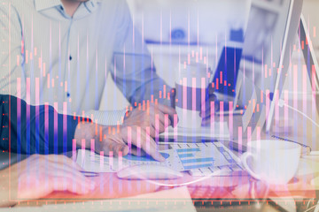 Multi exposure of chart with man typing on computer in office on background. Concept of hard work.