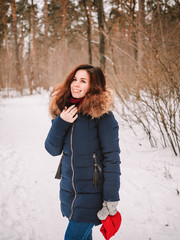A brunette girl with long hair walks through a snowy winter forest