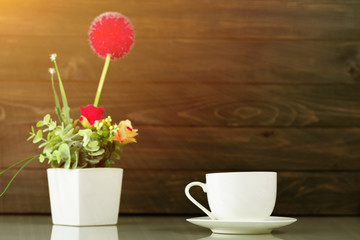 Coffee cup and Artificial flower vase bouquet over table