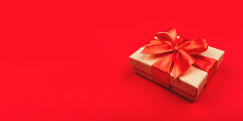 One cardboard gift box with bow on red background.