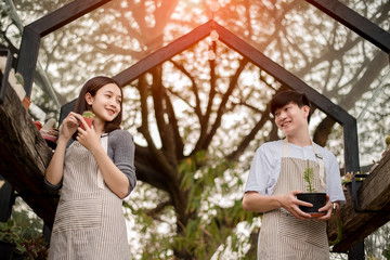 Gardeners working at plant nursery. In gardening business . Taking care of the plants. Happy to work on the field . Family business. Happy woman and man working with plants in a garden house