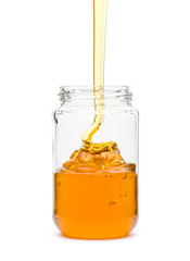 Honey spilling in glass jar, on white background