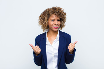 young woman african american smiling joyfully and looking happy, feeling carefree and positive with...