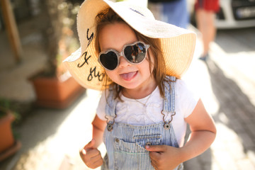 playful child in hat and sunglasses on street,trip